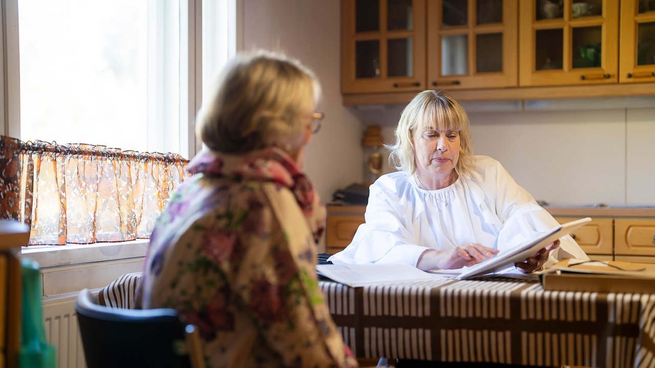 Valoisa olohuone, jossa on mintunvihreä sohva tyynyineen ja torkkupeittoineen sekä kalanruotoparketti, joka jatkuu oviaukosta ruokailutilaan puisten tuolien luo.