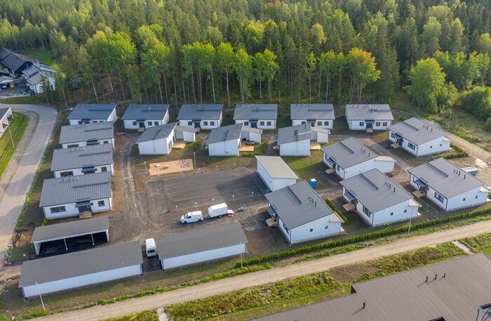 Ilmakuva Kaarinan Herrasniityn pientaloalueesta, jossa valkoiset talot ja autokatokset rajautuvat metsään.